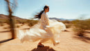 Woman in Flowing Dress Walking Through Desert Landscape