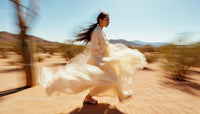 Woman in Flowing Dress Walking Through Desert Landscape