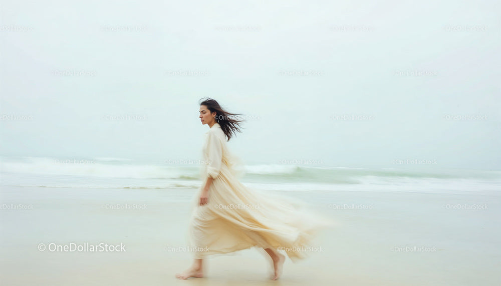 Woman in Flowing Beige Dress Walking by the Ocean