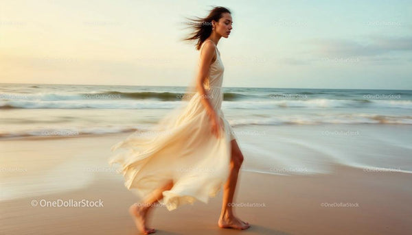 Elegancka kobieta w zwiewnej sukni spacerująca po plaży o zachodzie słońca