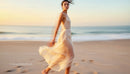 Elegant Woman in Flowing Dress on a Sunset Beach