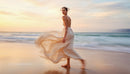 Elegant Woman in Flowing Dress at Sunset Beach