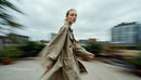 Woman in Beige Trench Coat on Rooftop with Cityscape View