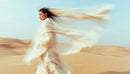 Elegant Woman in Flowing Dress Amidst Desert Dunes