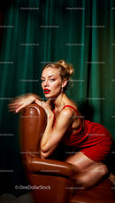 Glamorous Woman in Red Dress Posing on Leather Chair