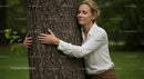 Woman Embracing Tree with Serene Expression in Nature