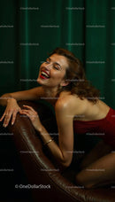 Joyful Woman in Red Dress Against Green Background