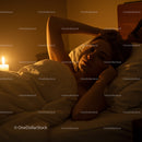 Woman Relaxing in Bed by Candlelight