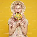 Young Woman with Lollipop and Floral Hat Against Yellow