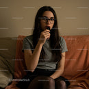 Pensive Young Woman Sitting Indoors in Cozy Setting