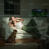Woman Relaxing with Headphones and Dog on Cozy Sofa