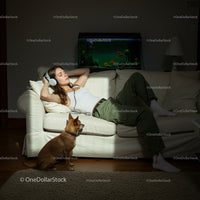 Woman Relaxing with Music Beside Dog and Aquarium