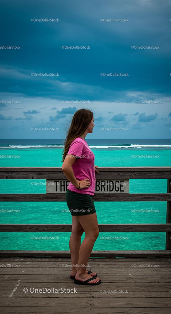 Young Woman Enjoying the Scenic Ocean View from a Pier