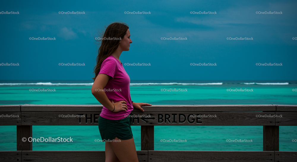 Woman Relaxing on Boardwalk Overlooking Turquoise Ocean
