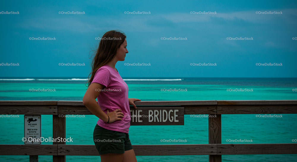 Woman in Pink Shirt on Ocean Bridge