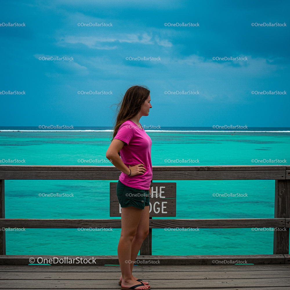 Woman on Wooden Deck Overlooking Turquoise Ocean