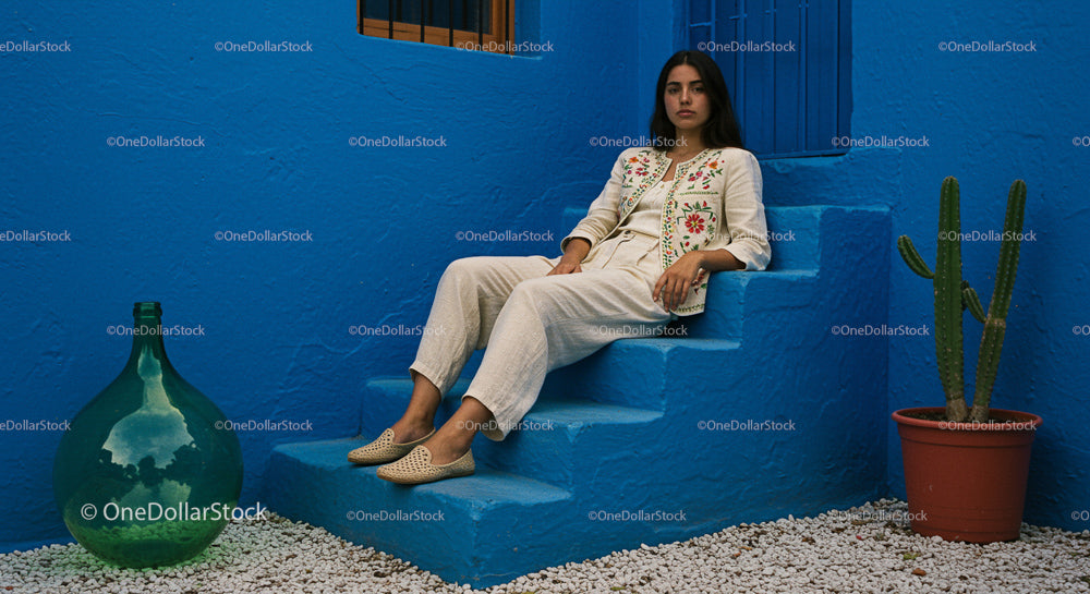 Woman in Embroidered Jacket Relaxing by Blue Wall
