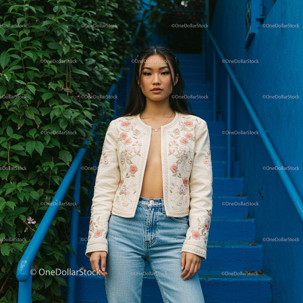 Woman in Embroidered Jacket on Blue Stairs with Green Foliage