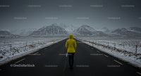 Traveler in Yellow Jacket on Snowy Mountain Road