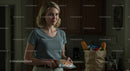 Smiling Woman Holding Groceries in a Cozy Kitchen