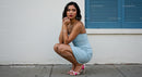 Stylish Woman in Blue Summer Dress Crouching by Wall