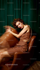 Elegant Woman Posing on Brown Leather Chair in Glamorous Setting