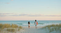 Couple Walking Along Serene Beach at Sunset