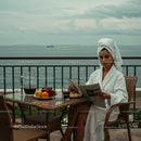 Woman in White Bathrobe Relaxing on Balcony with Ocean View
