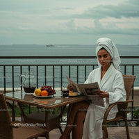 Woman in White Bathrobe Relaxing on Balcony with Ocean View