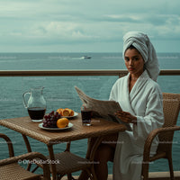 Woman in Bathrobe Enjoying Breakfast on Oceanfront Balcony