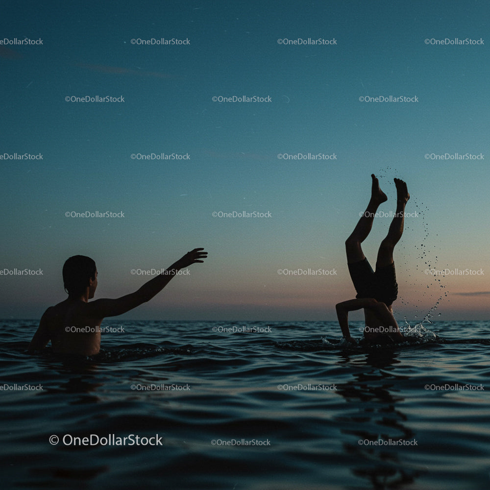 Sylwetki postaci bawiących się w oceanie o zachodzie słońca