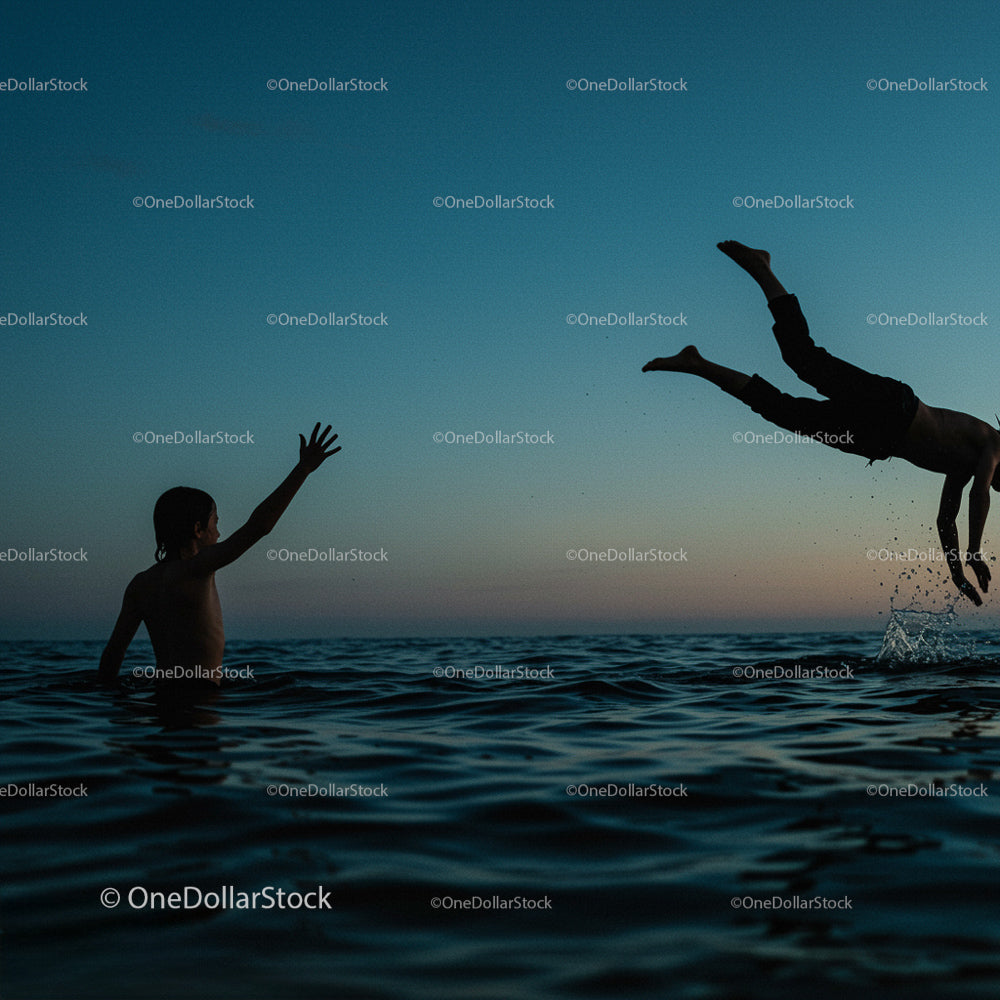 Silhouette of Children Playing in Ocean at Sunset