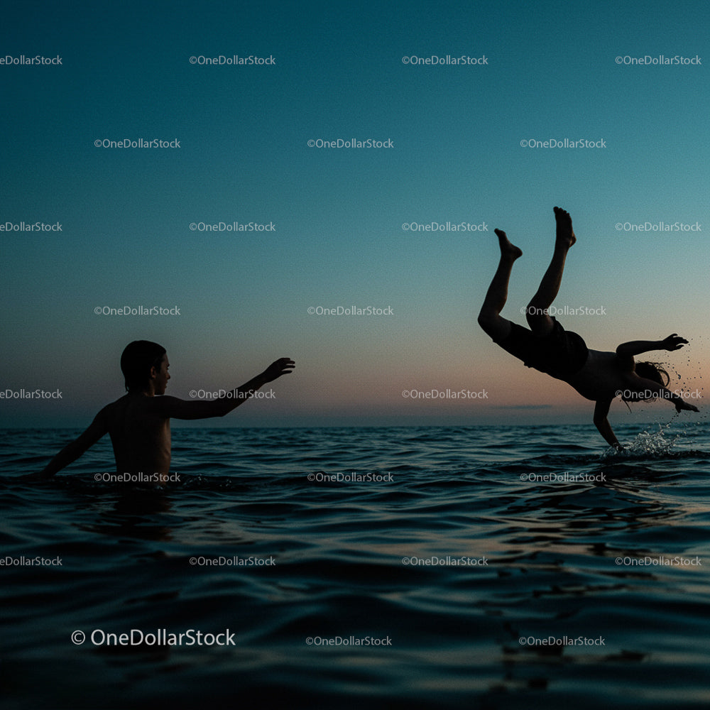 Silhouetted Boys Playing in Ocean at Sunset
