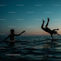 Silhouetted Boys Playing in Ocean at Sunset