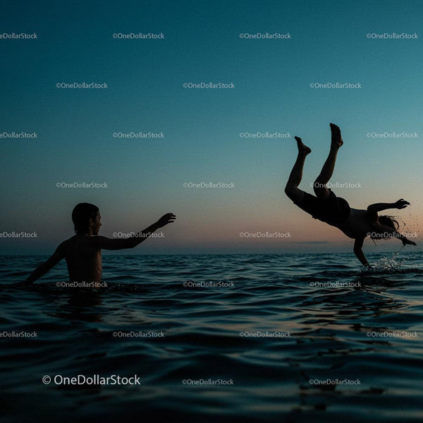 Silhouetted Boys Playing in Ocean at Sunset