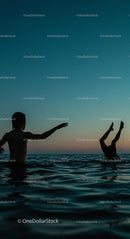 Silhouetted Youth Playing in Ocean at Sunset