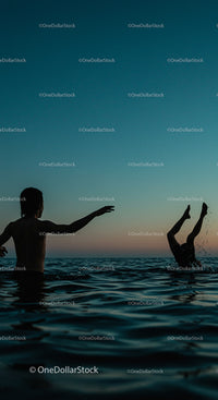 Silhouetted Youth Playing in Ocean at Sunset