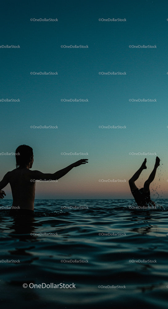 Silhouetted Youth Playing in Ocean at Sunset