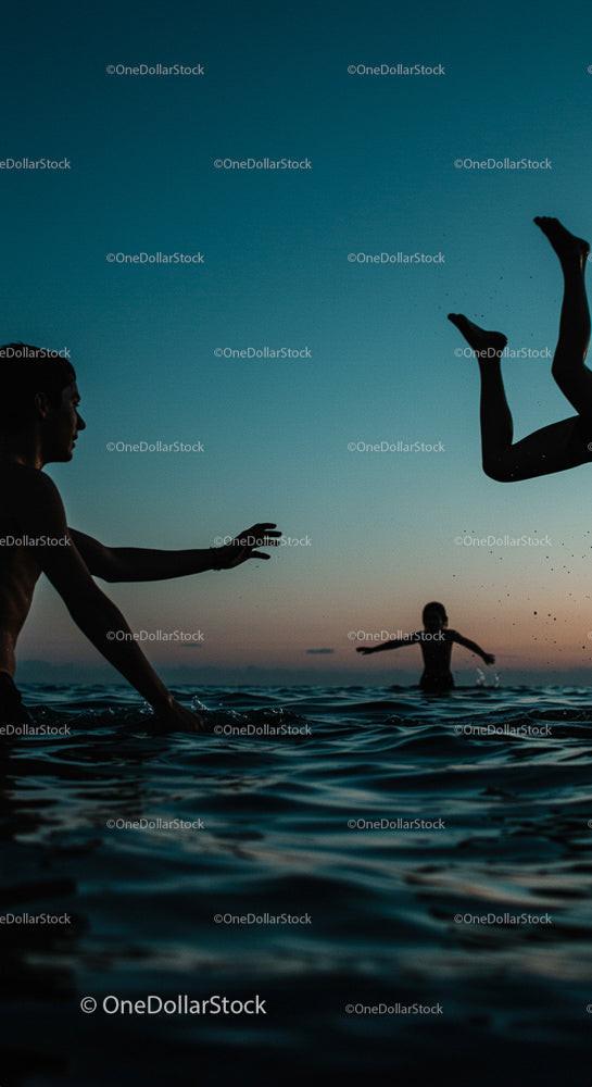 Silhouetted Friends Playing in the Ocean at Sunset