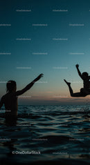 Silhouetted Figures Enjoying a Sunset Swim in the Ocean