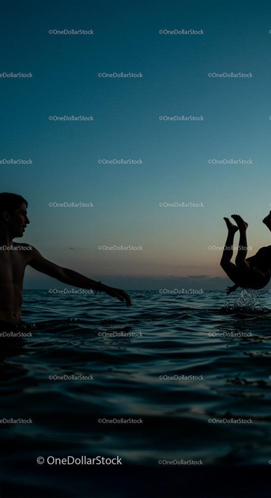 Silhouettes Enjoying a Playful Swim at Sunset