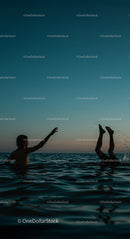 Silhouettes Playing in Ocean at Sunset