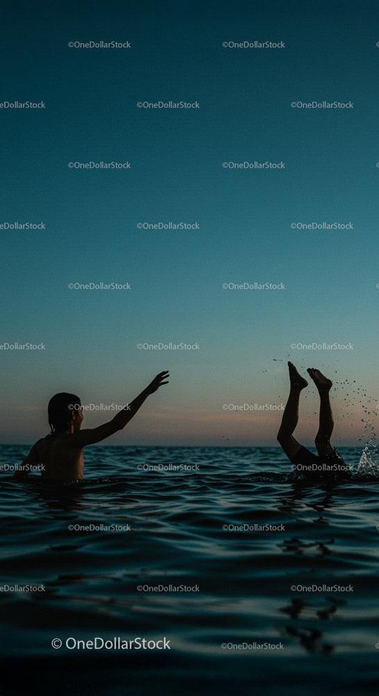 Silhouettes Playing in Ocean at Sunset