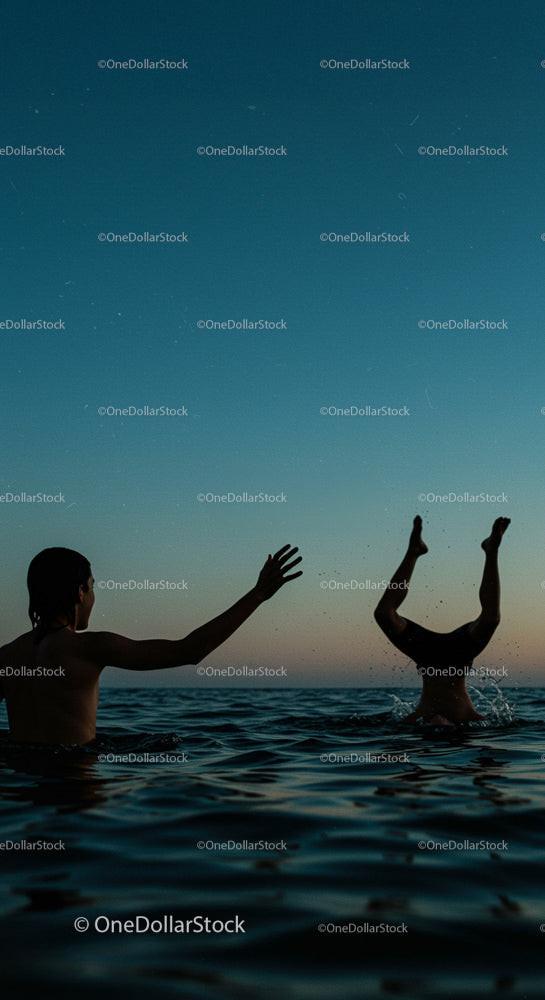 Silhouettes Swimming in the Ocean at Sunset