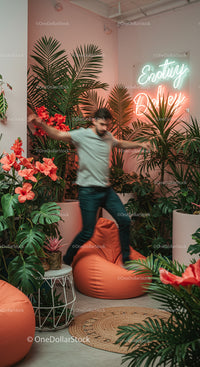 Man Enjoying Indoor Jungle with Lush Hibiscus and Neon Sign