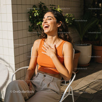 Laughing Woman in Orange Top Amidst Sunlit Setting