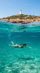Diver in Clear Waters with Lighthouse Overhead