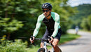 Cyclist Riding Along a Scenic Forest Road in Daylight