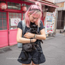 Young Woman with Pink Hair Holding a Black Cat in the City