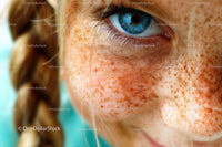 Close-Up of Blue-Eyed Child with Freckles and Braided Hair